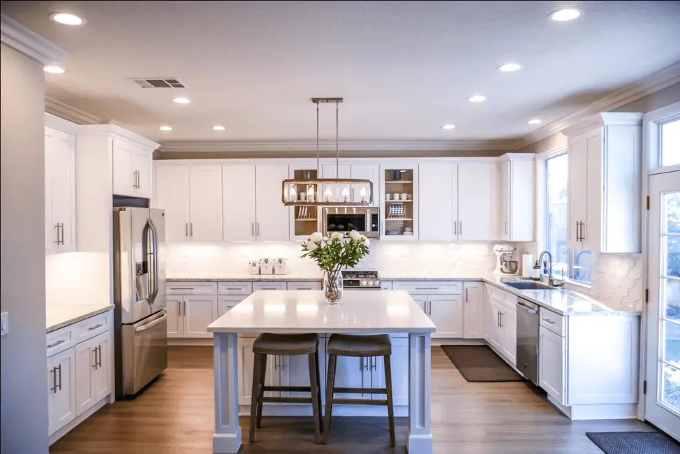 A wide shot of a white kitchen with clean quartz countertops